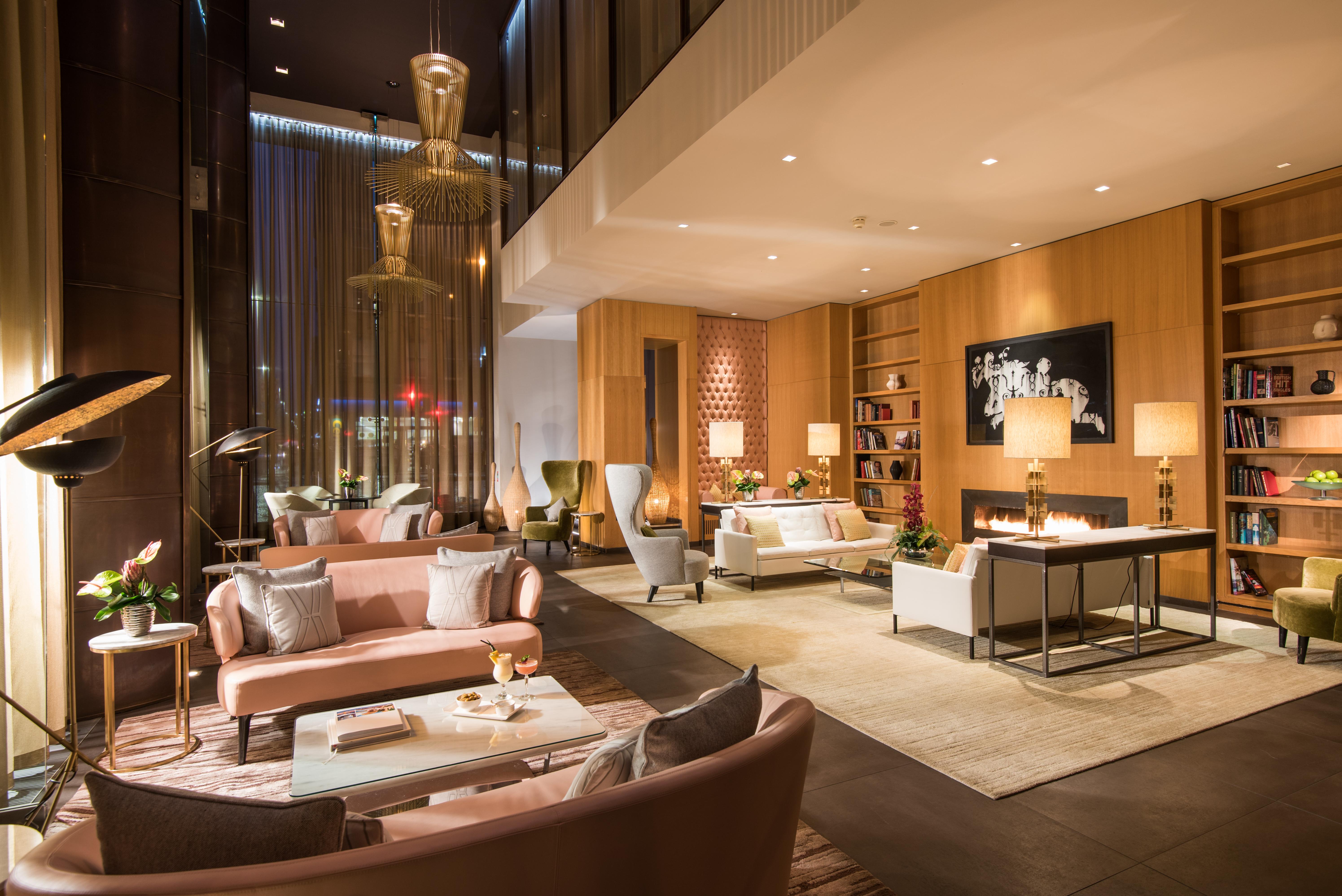 The Fitzwilliam Hotel Belfast Bagian luar foto The photo shows a modern and elegant lobby or lounge area. The space features a mix of contemporary and cozy furniture, including light-colored sofas and armchairs arranged around small tables. There are decorative elements like vases with flowers, a